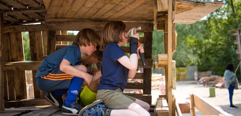 drie kinderen timmeren aan een hut