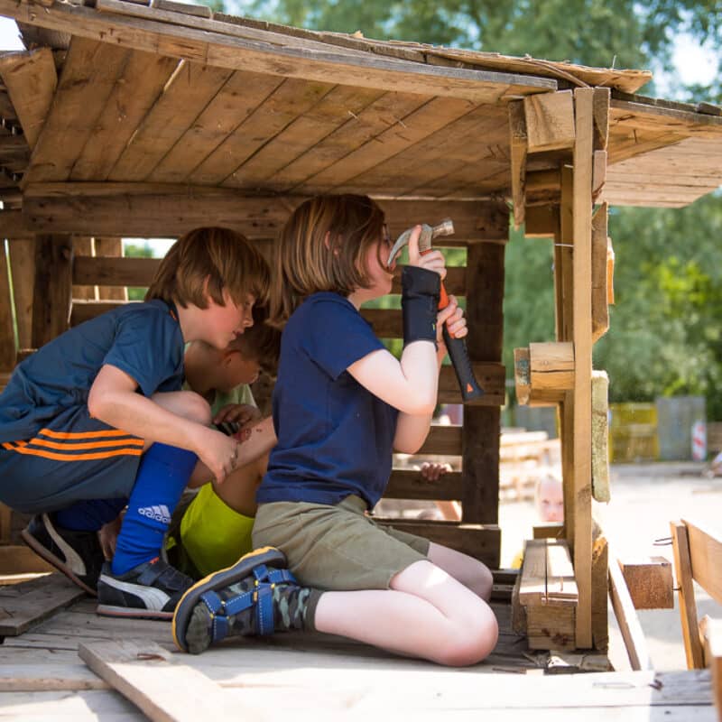 drie kinderen timmeren aan een hut