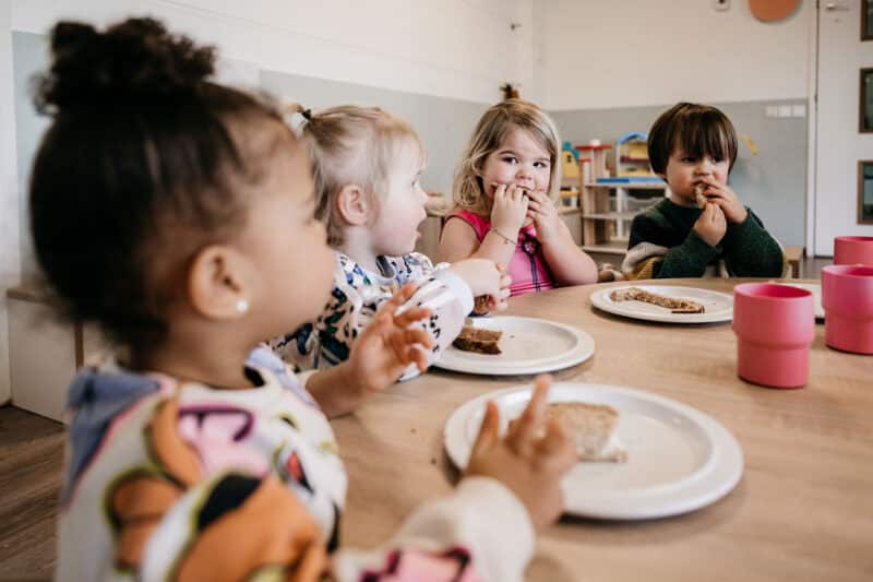 peuters eten gezamenlijk aan tafel op het kinderdagverblijf